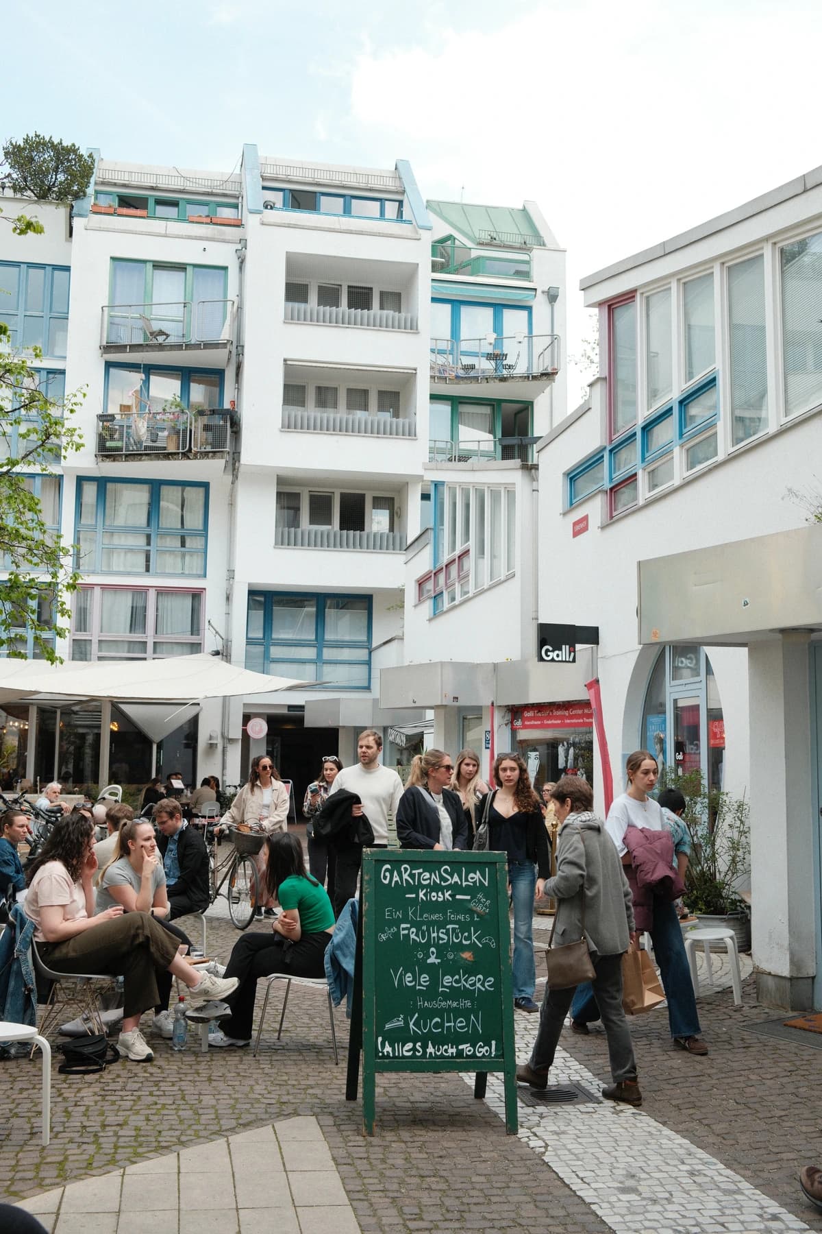 The Amalienpassage courtyard in Munich's Maxvorstadt, busy with people at café tables, where Humpback Whale is tucked away