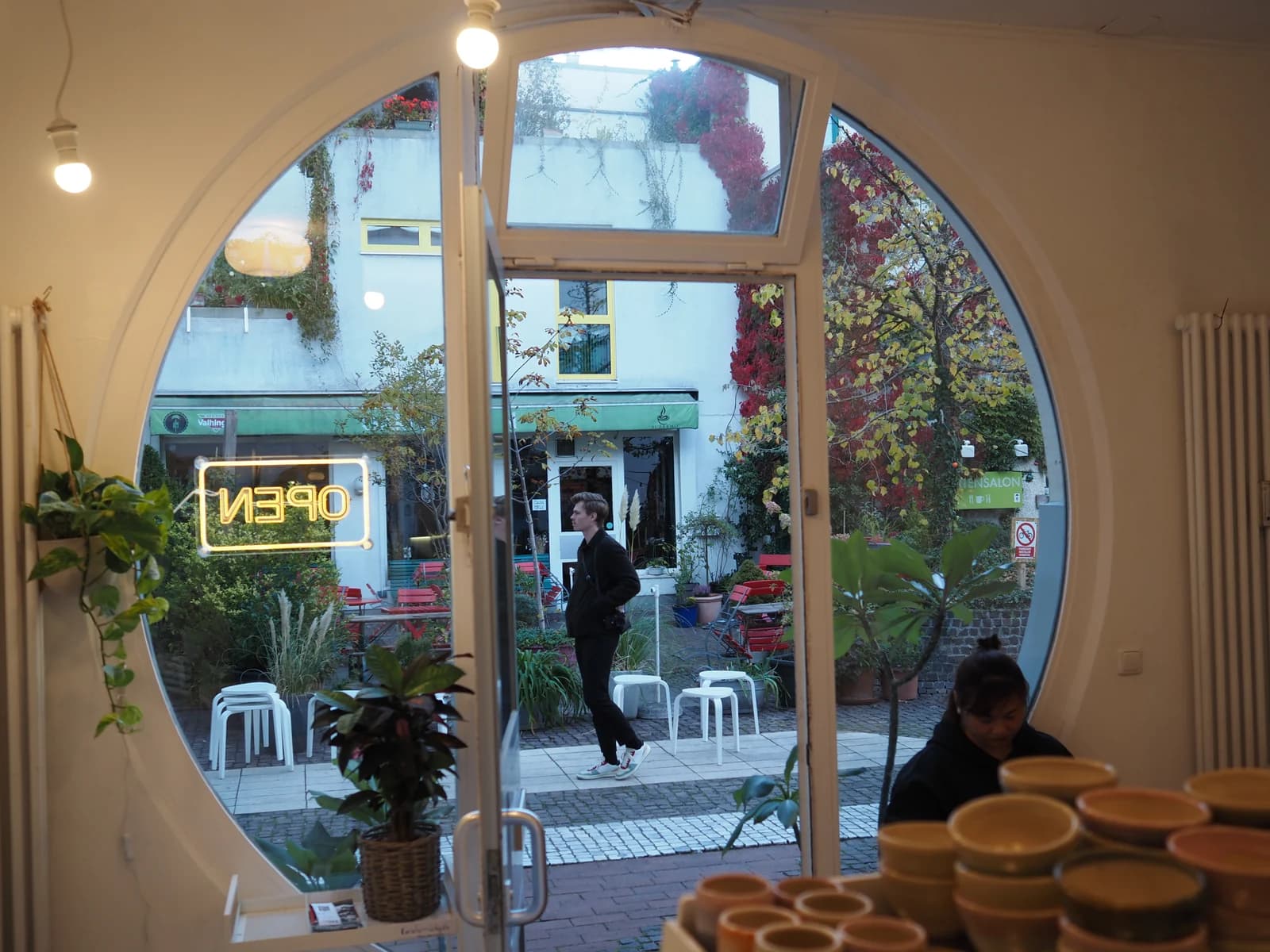 The Amalienpassage courtyard in autumn, seen from inside Humpback Whale Coffee through its round porthole door, Munich